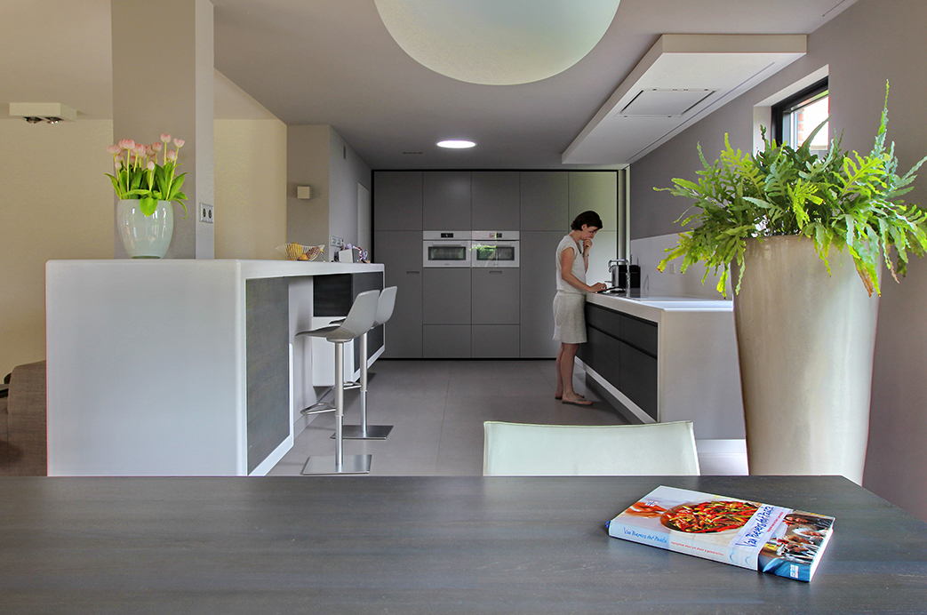 Keuken met bar en aanrecht van Hi-macs, tafel en keukendeurtjes van vergrijsd moeraseiken ontwerp Leonardus interieurarchitect
