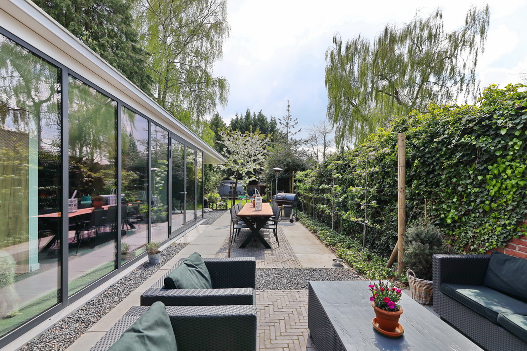 Aanbouw met aluminium glaspui waarin de lente tuin gespiegeld wordt door Paul de Bruijn en Leonardus interieurarchitecten.