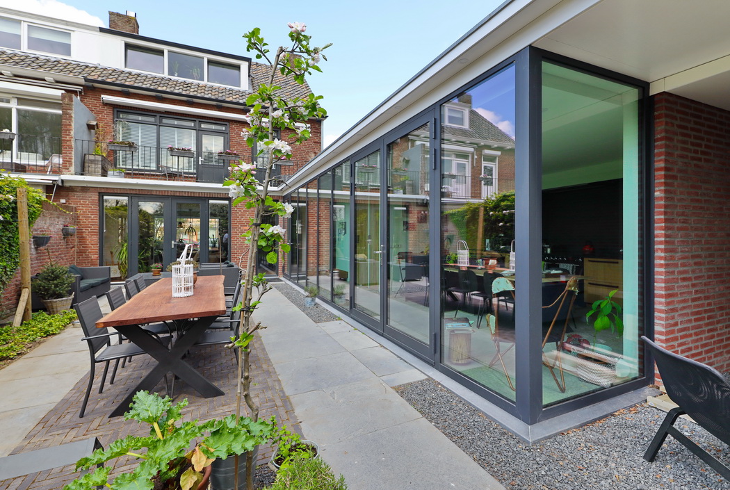 Een aanbouw ontworpen door Leonardus met moderne aluminium kozijnen met daarin opgenomen de keuken gezien vanuit de tuin.